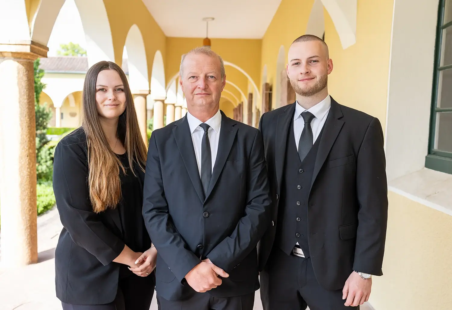 Bestatter Mühlacker - Foto der zwei Generation des Familienunternehmens Gamper. In der Mitte steht der Gründer des Bestattungsinstituts. Rechts daneben steht sein Sohn und links seine Tochter